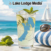 A tall glass of lemonade with mint and lime sits against a scenic beach backdrop.