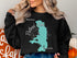 Black sweatshirt with "Beautiful Flathead Lake Montana" text and lake graphic.