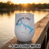 A white insulated wine tumbler featuring a blue map of Skiatook Lake, Oklahoma, resting on a wooden dock.