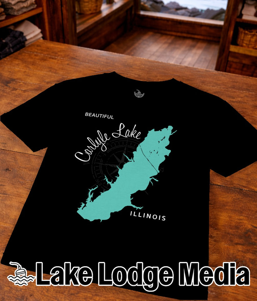 Black t-shirt with teal Carlyle Lake map and compass, "Illinois" text, and "Lake Lodge Media" logo.