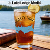 Glass with ice tea, compass design, and lake outline, beside a book.