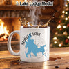 White mug with Shaver Lake map graphic, steaming coffee, fireplace, and Christmas tree background.