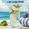 Glass with drink, lime, mint, and compass design, beach background.