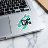 Turquoise sticker on laptop reads "Placid Life" with © Lake Lodge Media LLC