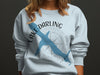 Light blue sweatshirt with blue Lake Darling shape over compass and "Iowa" text.