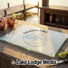 Tempered glass cutting board featuring a Norris Lake compass map design, resting on an outdoor wooden bar.