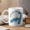 White mug with Augur Lake New York map and compass graphic, steaming hot.