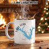 White mug with "Lake Fork Texas" design and compass rose, steaming coffee splashing.