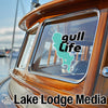 "gull Life" sticker on a wooden boat window with "Lake Lodge Media" text below.