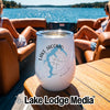 A white stemless wine tumbler with Lake Jacomo Missouri graphic sits on a wooden boat table.
