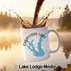White mug with Calaveras Lake Texas map and compass design, with coffee splashing.