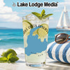 Glass with a drink, lime, mint, and sunglasses on a beach with a sailboat.