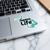 Spoon Life sticker in black and teal on a laptop keyboard.