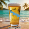 Glass of beer with "Grapevine Lake Texas" map and compass graphic on beach.