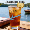 A pint glass filled with iced tea and a lemon slice, sitting on a wooden table outdoors.