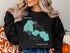 Black sweatshirt with "Beautiful Forest Lake" text and Minnesota map graphic.