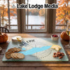 A glass cutting board featuring a map of Lake Erie and Pennsylvania, surrounded by crackers, cheese, and fruit.