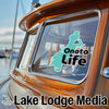 Teal "Onota Life" sticker on a wooden boat window with "Lake Lodge Media" text.
