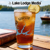 Iced tea in a glass with Lake Shasta map and compass graphic, by a lake.