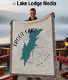 Man holding a throw blanket featuring a teal map outline of Trout Lake, New York.