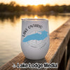 A white insulated wine tumbler featuring a blue outline of Lake Ontario and text that reads Lake Ontario Canada rests on a wooden dock with a lake sunset background.