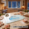 A glass cutting board with a blue Grenada Lake map design rests on a kitchen counter amid baking supplies.