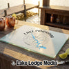 A glass cutting board featuring a compass design and Lake Panorama, Iowa, sits on a wooden outdoor bar.