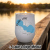A white tumbler featuring a blue lake silhouette and compass design rests on a wooden dock.