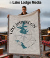 Man holding a Lake Disharoon, Georgia woven blanket with a compass rose design.