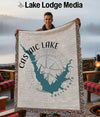 Man holding a throw blanket with a map of Castaic Lake, California, and a compass.