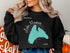 Black sweatshirt with "Beautiful Lake Manawa Iowa" map graphic.