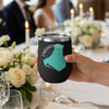 Black tumbler with Emerald Lake Canada map and compass graphic held at a table setting.