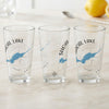 Three clear glasses with blue maps and compass designs for Shoal Lake, Ontario.