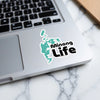 Sticker with turquoise map outline and "Minong Life" text on a laptop.