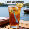 A tall glass of iced tea garnished with a lemon slice sits on a wooden table outdoors.