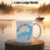 White mug with Augur Lake map and compass design on a waterfront background.
