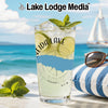 Tall glass of lemonade with lime and mint on a beach with a sailboat.
