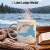 White mug with Lake Gregory California map and compass design on window ledge.