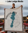 Man holds Barlow Lake Michigan woven throw blanket with teal lake outline.