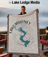 Man holding Lake Whitney Texas map throw blanket with compass design and tasseled edges.
