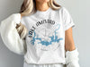White t-shirt with "LAKE AMISTAD TEXAS" text and a compass rose map design.