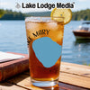 Iced tea in a glass with a lemon slice on a wooden table by a lake.