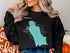 Black sweatshirt with a teal outline of Lake Chelan, Washington.