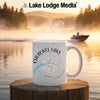 White mug with "Cherokee Lake Tennessee" and compass design by a lake.