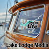 "Cedar Life" graphic on a wooden boat window with "Lake Lodge Media" text below.