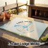 A glass cutting board featuring a Lake Mead, Arizona map and compass design on a wooden table.
