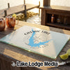A glass cutting board featuring a blue map of Castaic Lake, California, sits on a wooden dock.
