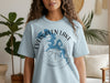 Light blue t-shirt features "Evergreen Lake" text, a blue lake map, and compass rose graphic.
