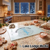 A clear glass cutting board with a blue Candlewood Lake compass design rests on a kitchen counter during the winter holidays.