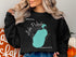 Black sweatshirt with teal Lake Pulaski, Minnesota map and compass design.